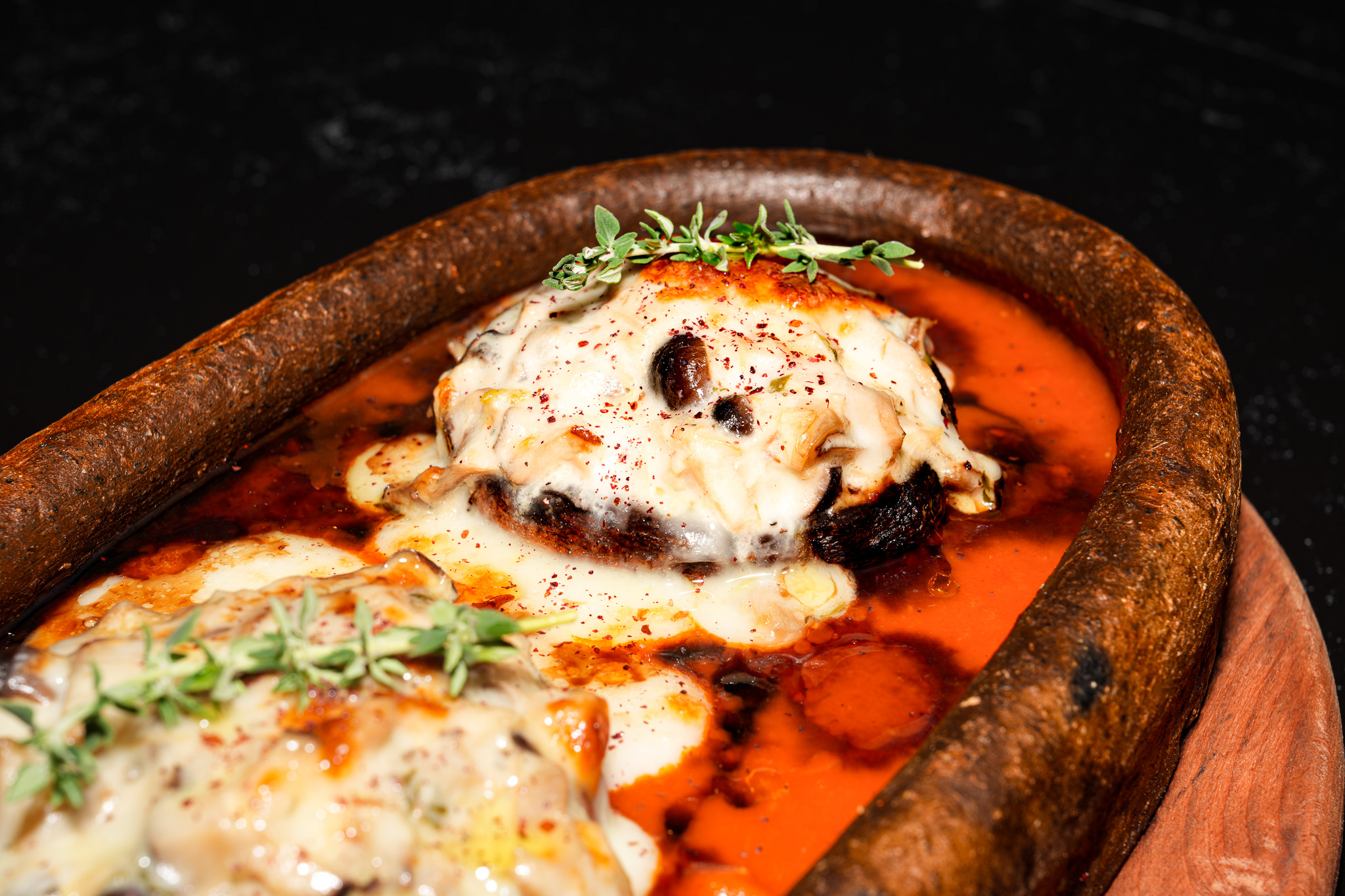 Cheese-topped aubergine in tomato sauce, served in a clay dish