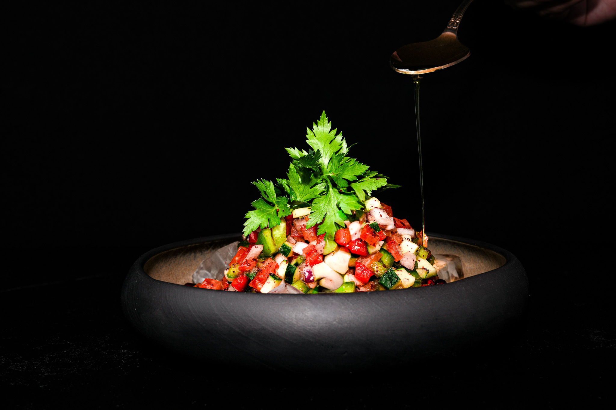 Dressing being poured over chopped salad with pomegranate