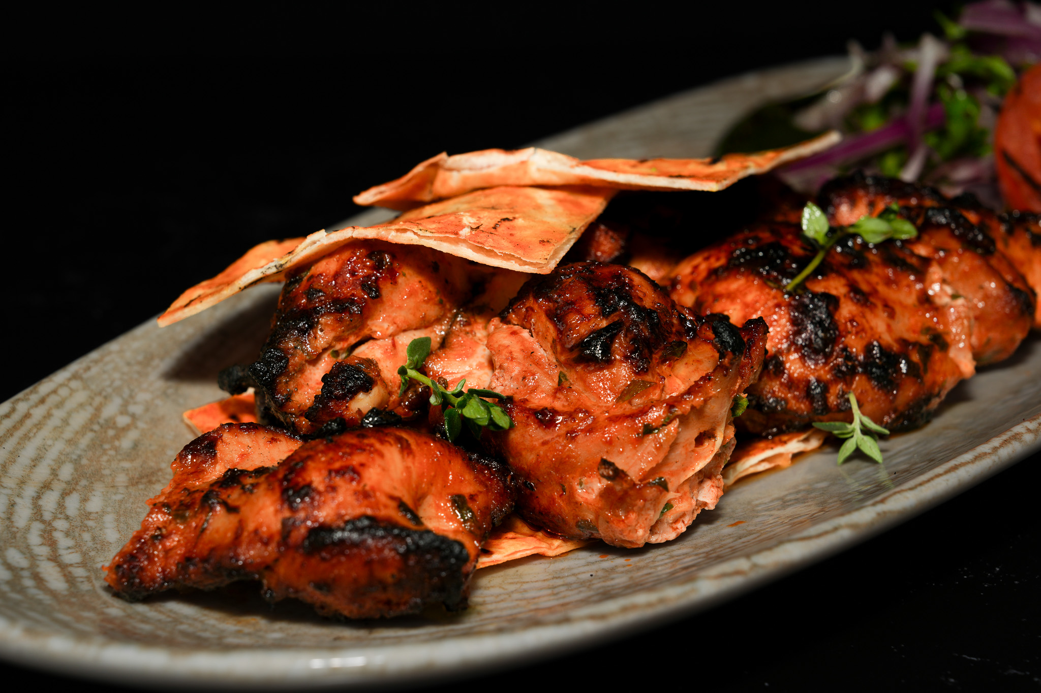Close-up of chargrilled chicken with herbs and flatbread