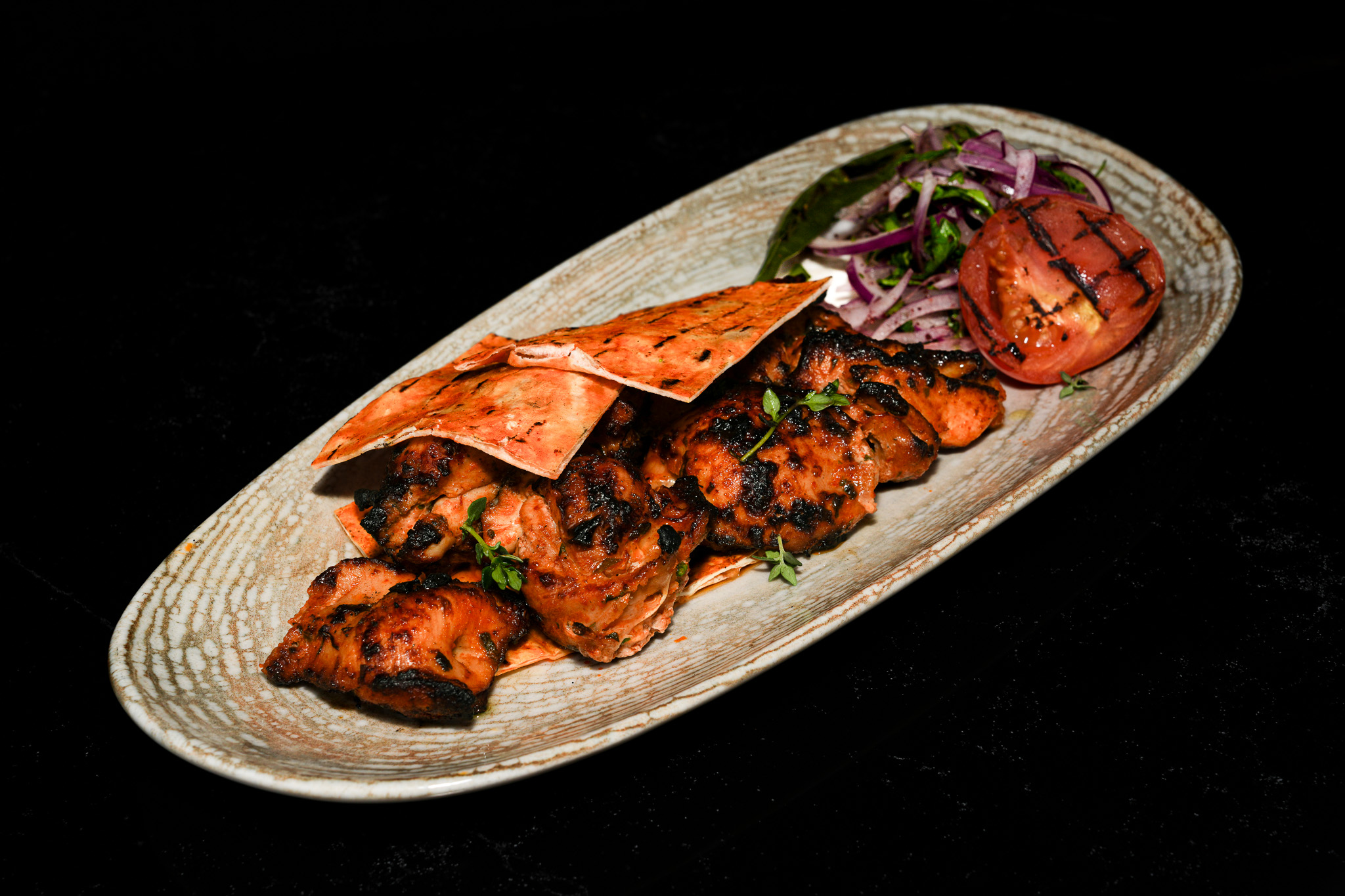 Grilled chicken platter with flatbread, tomato, and onion salad