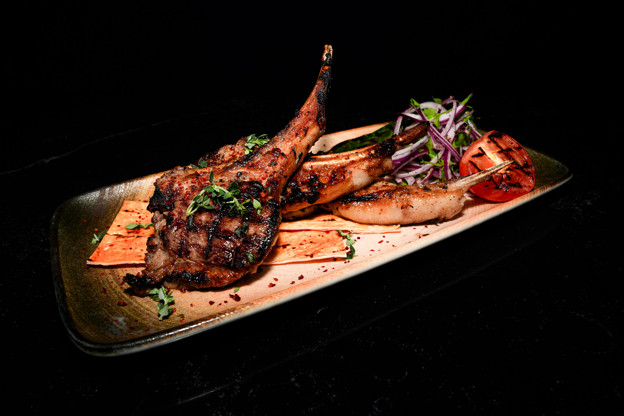 Grilled lamb chops with flatbread, tomato, and onion salad