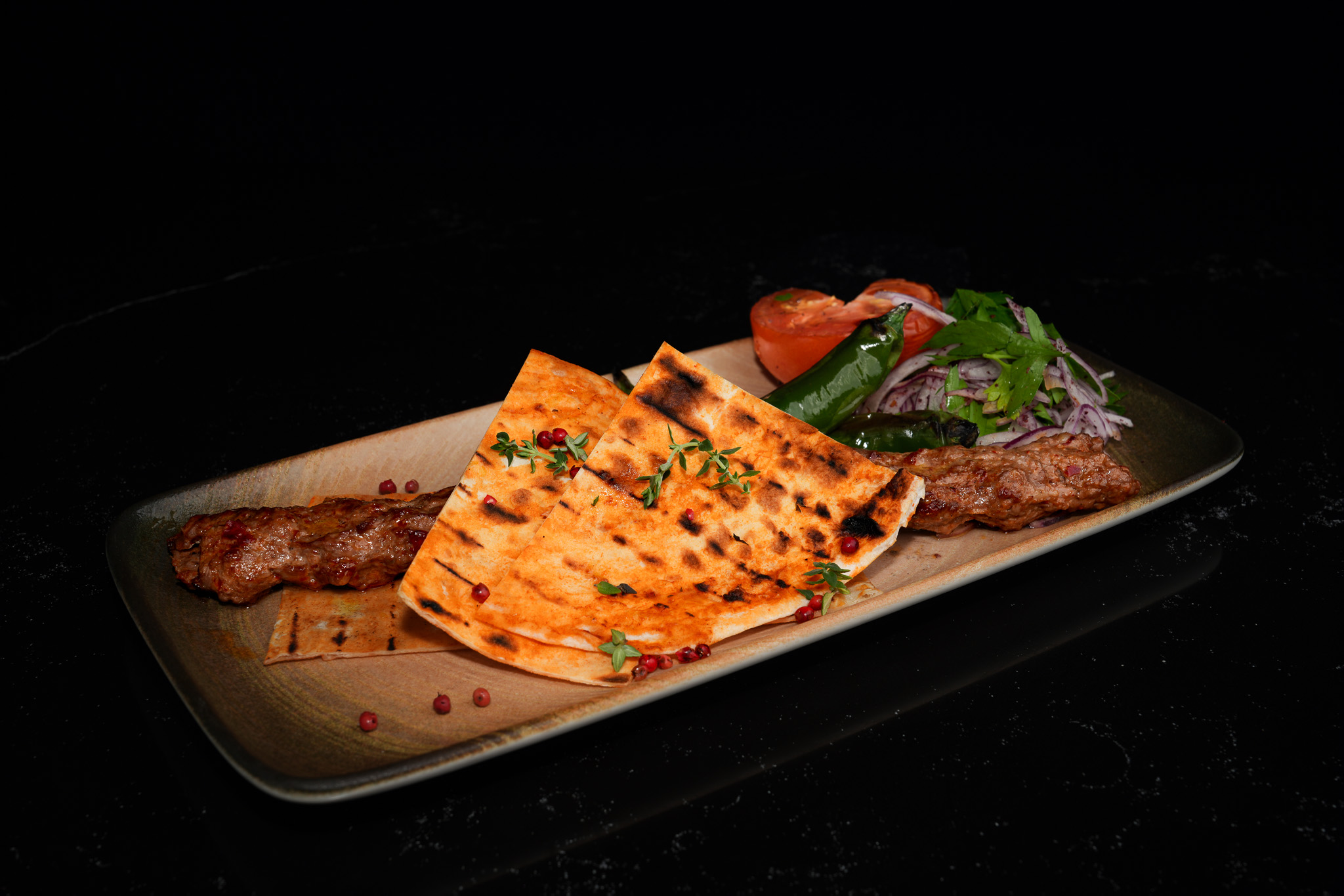 Grilled kebab served beneath folded flatbread with onion salad