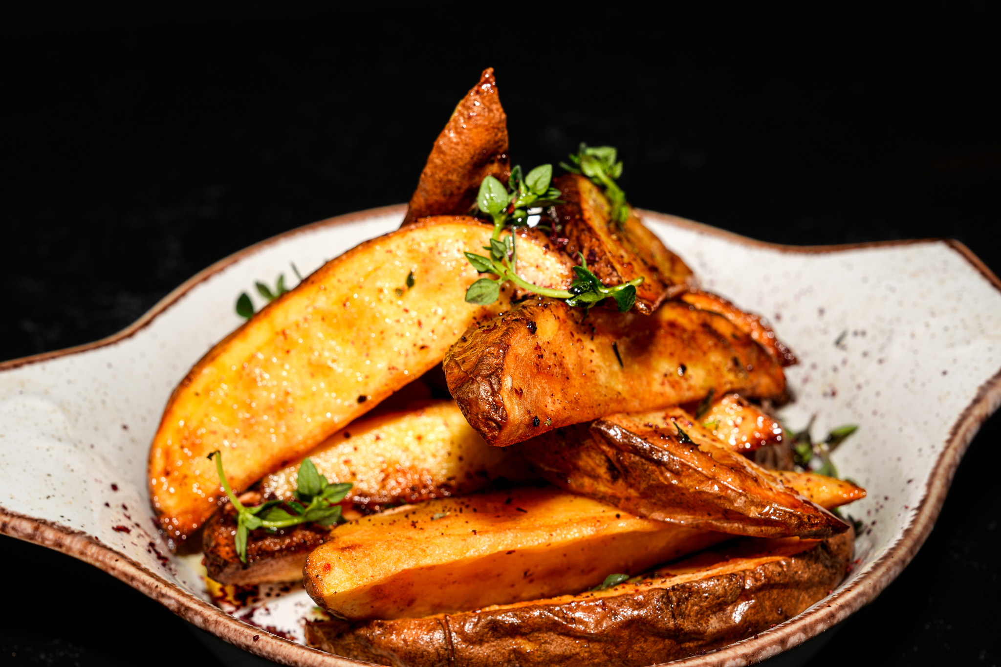 Close-up of golden potato wedges with chopped herbs
