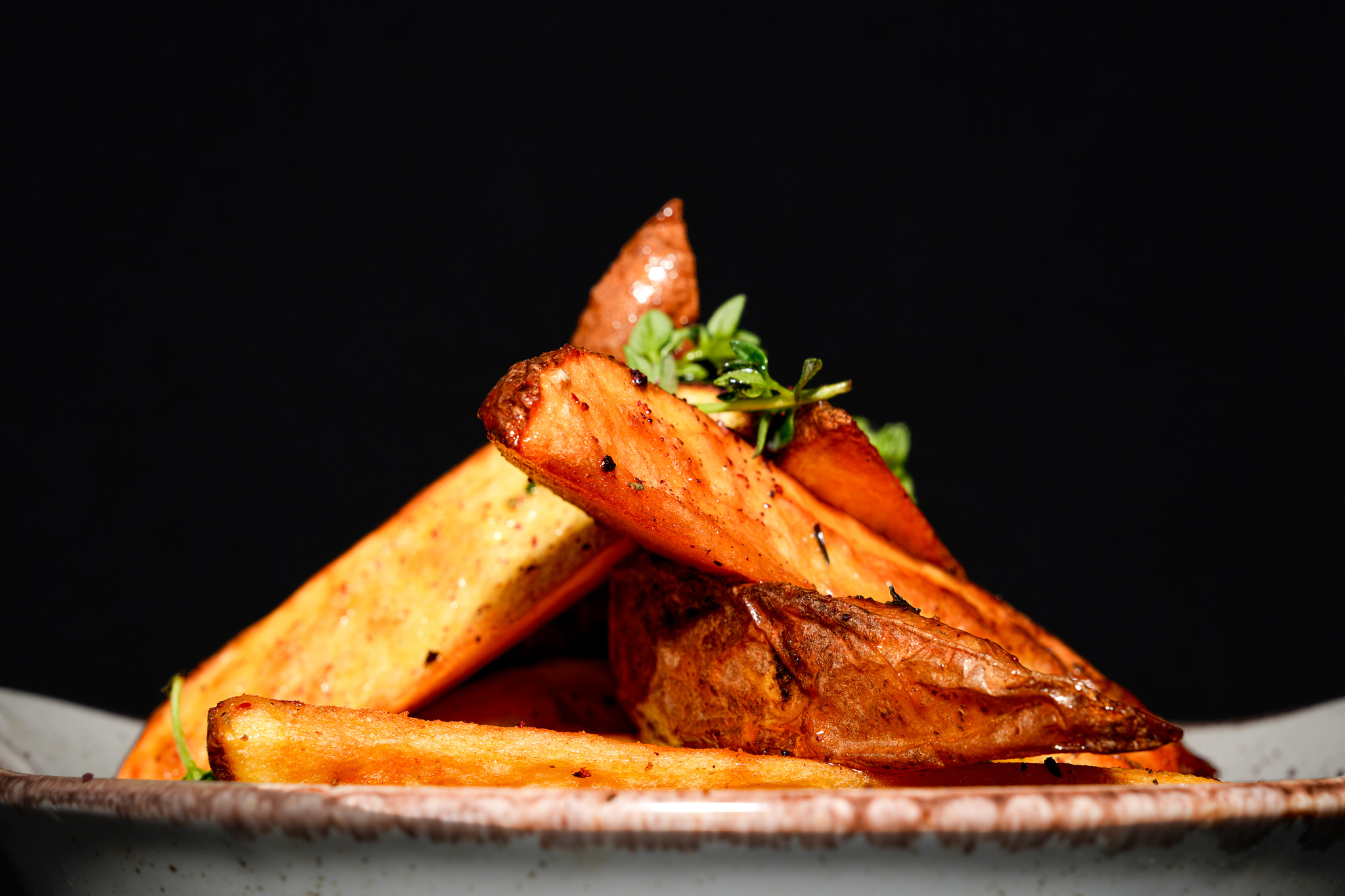 Golden potato wedges stacked on a ceramic plate