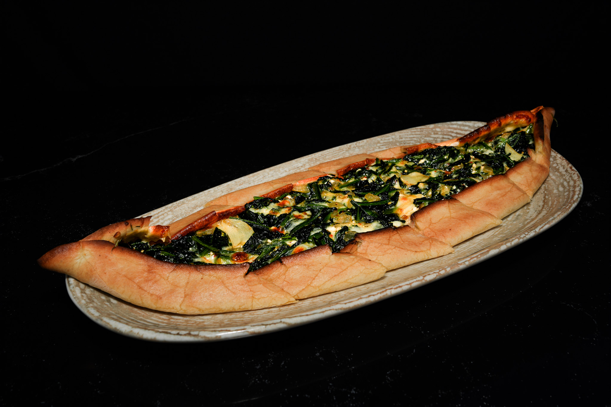 Spinach and cheese pide on a serving board