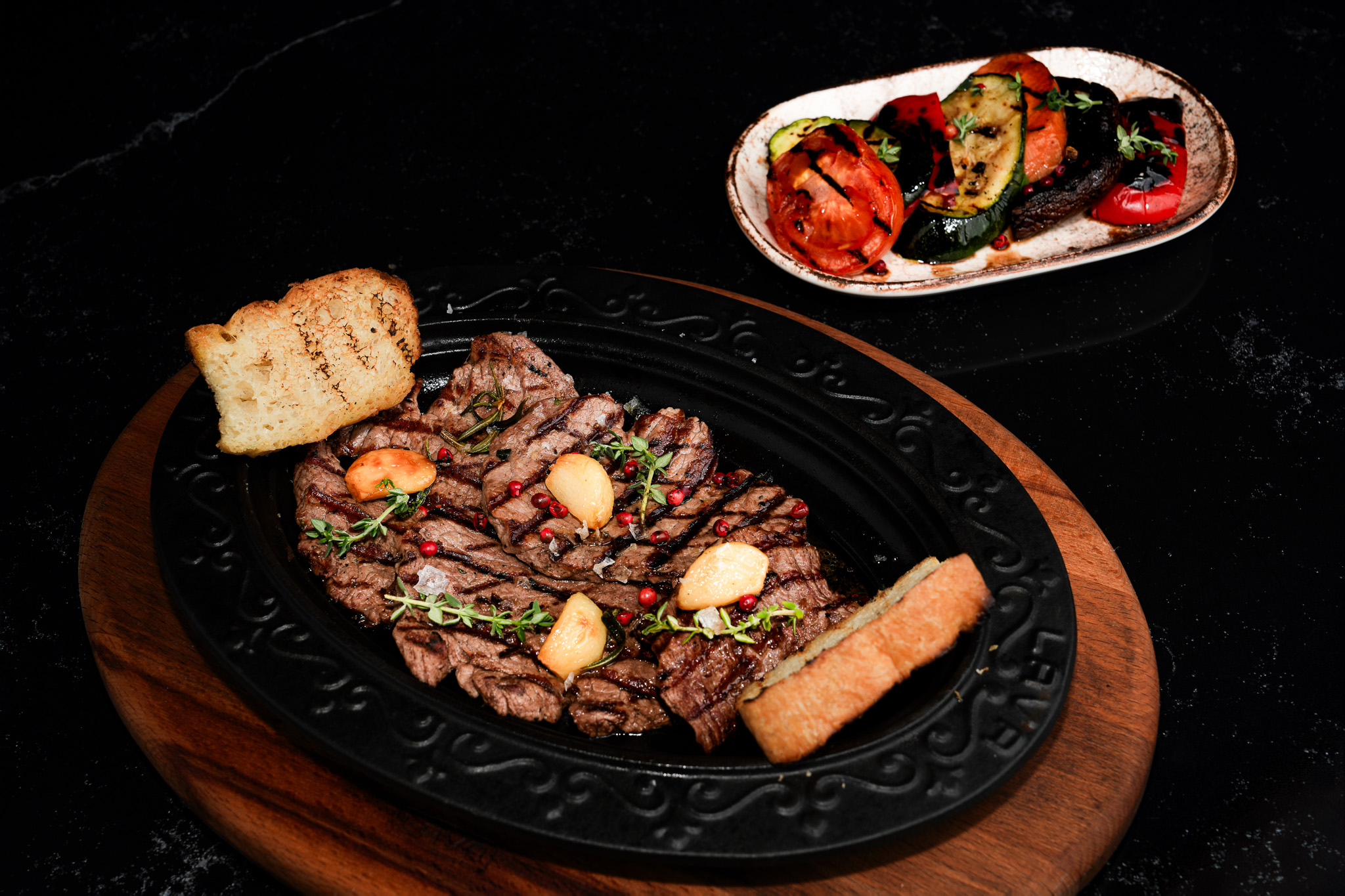 Grilled steak and garlic with vegetables on the side, viewed from above