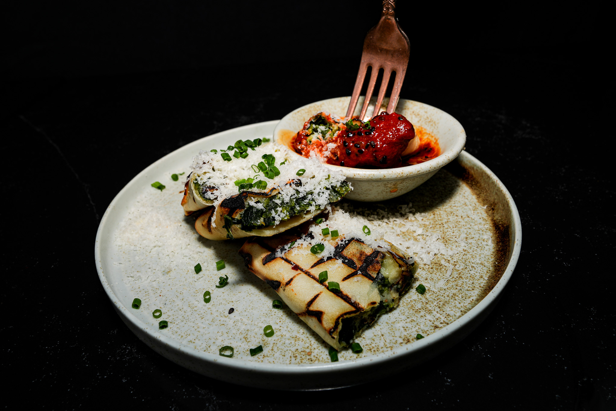 Stuffed flatbread served with a red dipping sauce