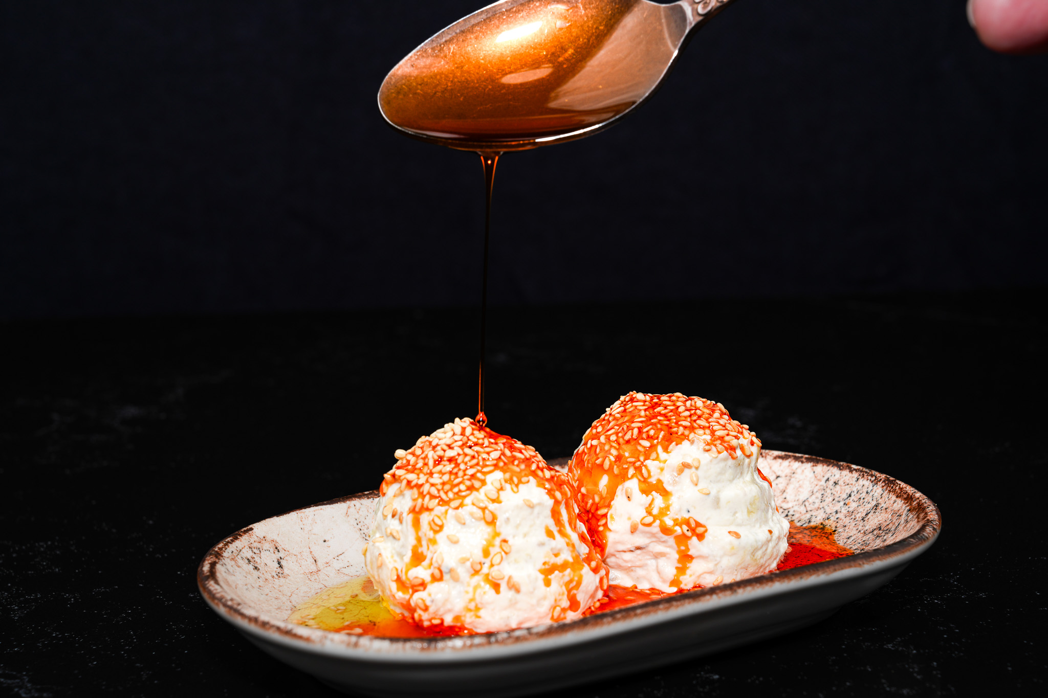 Chilli oil being spooned over scoops of yogurt