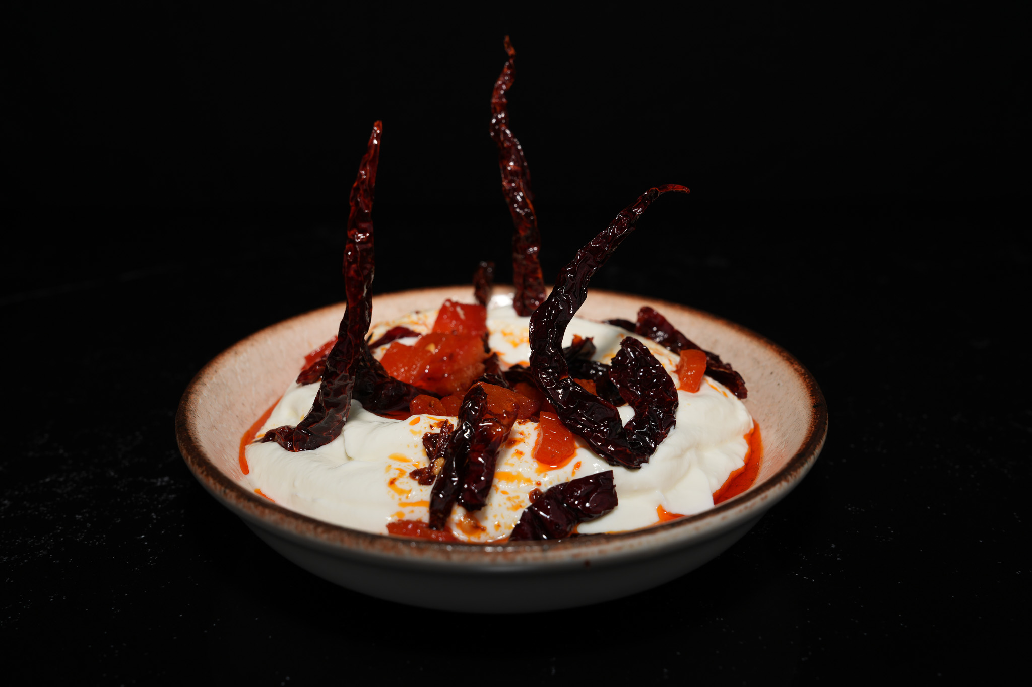 Yogurt topped with dried peppers and red sauce